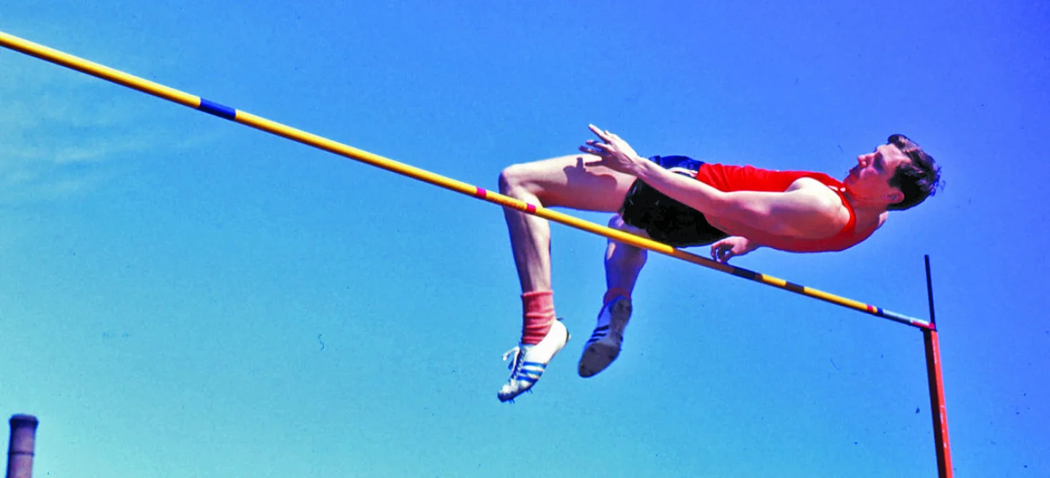 High jumper arched over the bar, showing how center of gravity physics lets the body's center of gravity pass beneath the bar